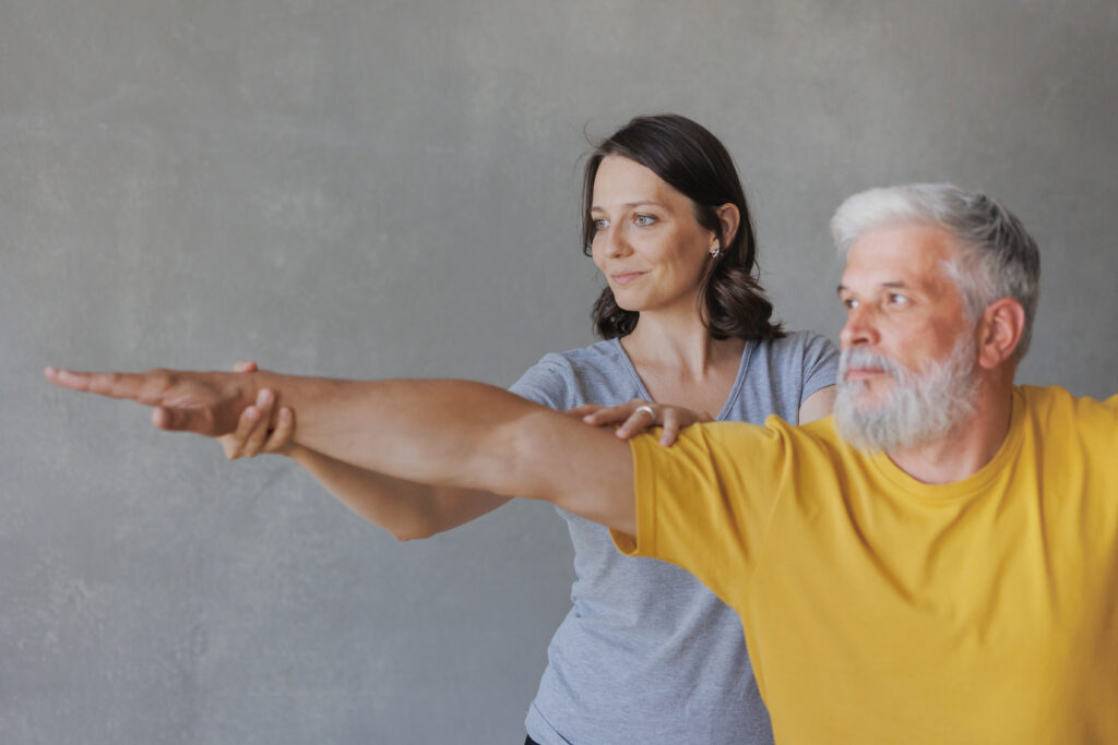 man and woman do yoga in sports studio. coach and senior are engaged in physical exercises for back health.